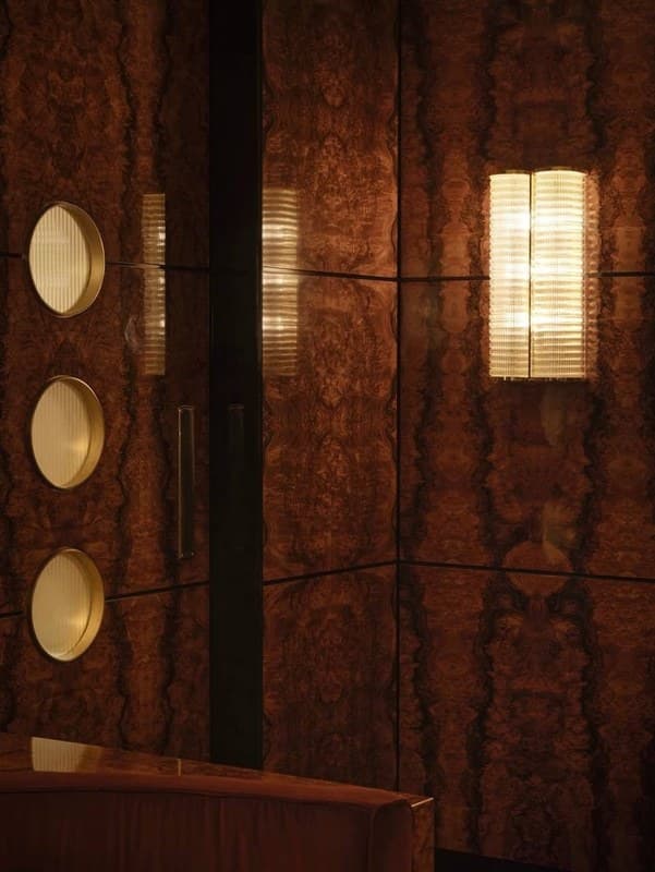 Walnut-panelled lounge lit by a glowing sconce